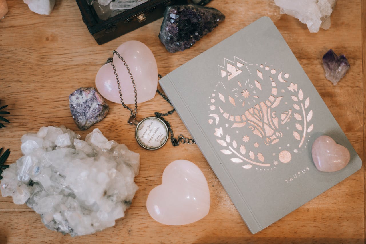 Taurus-themed notebook surrounded by heart-shaped and raw crystals on a wooden surface, evoking tranquility.